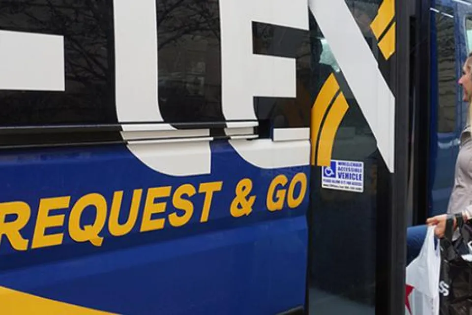 Blue FLEX bus with "Request & Go" text on side, woman rider boarding